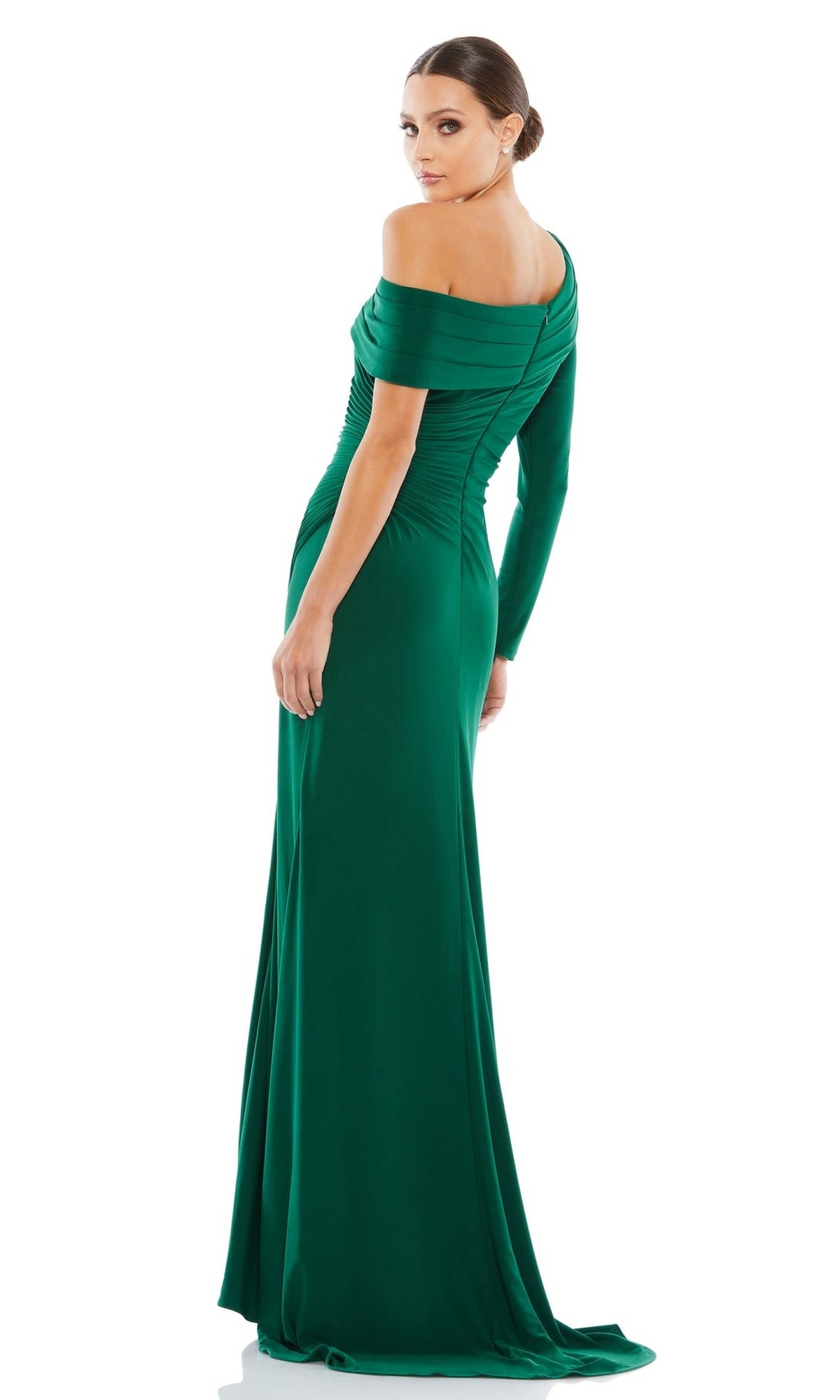 A woman stands against a white background, looking over her shoulder while wearing the Mac Duggal 26570: a fitted green, one-sleeve drop-shoulder long formal dress.